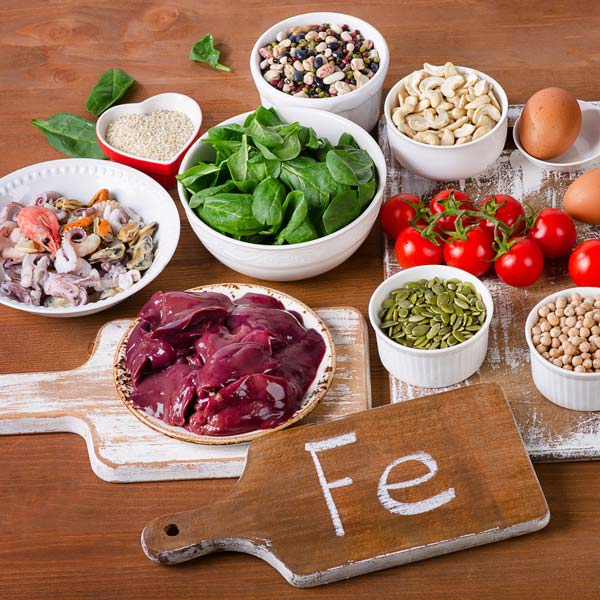 Assorted iron-rich vegetables including spinach, kale, broccoli, and peas, displayed on a wooden surface—nutrient-dense options for boosting iron intake naturally.